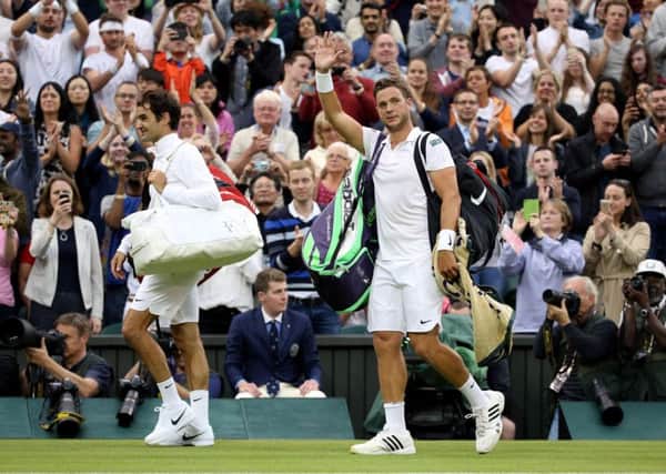 Marcus Willis waves as he leaves Centre Court with Roger Federer following defeat at Wimbledon.