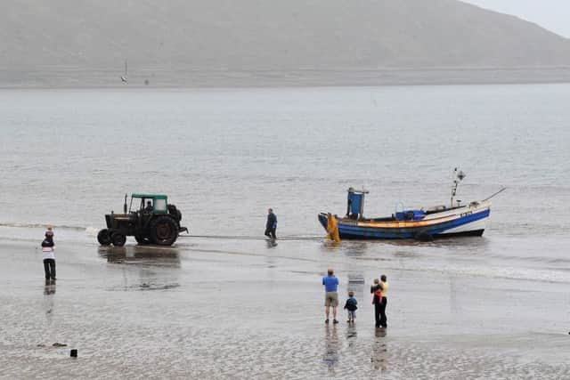 Visitors to Filey watch as one of the last working Filey Coble is brought ashore after a fishing trip.
Picture by Gerard Binks.