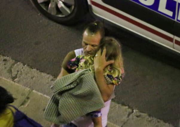 A man holds a child after a truck plowed through Bastille Day revelers in the French resort city of Nice.