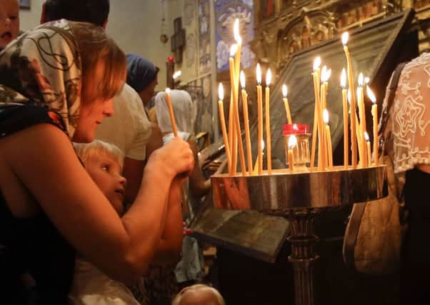 A woman and her children light candles during a mass at the Saint Nicolas Orthodox church in Nice following last week's attack. (AP Photo/Luca Bruno)