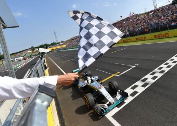 FIRST HOME: Mercedes' Lewis Hamilton crosses the finish line to win the F1 Hungarian Grand Prix at the Hungaroring circuit. Picture: Andrej Isakovic/AP