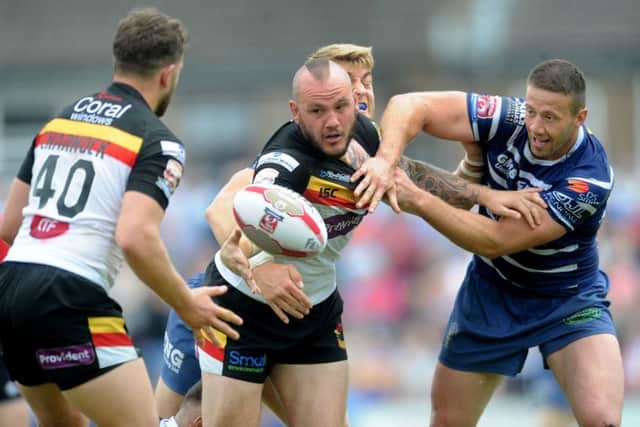TOUGH GOING: Bradford Bulls' Dale Ferguson, passes on the ball towards Lewis Charnock, while been pulled back by Featherstone Rovers Steve Snitch. Picture James Hardisty.