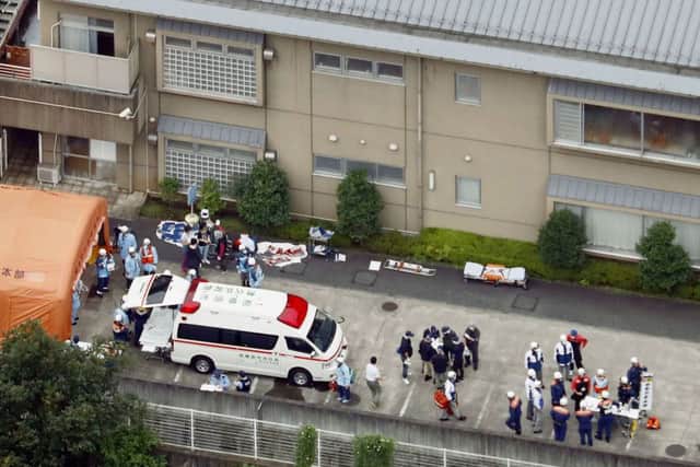 Ambulance crew and police officers  are seen outside the facility. (Kyodo News via AP)