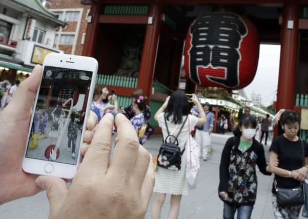 A man tries to catch a Pikachu, a Pokemon character, while he plays "Pokemon Go" in front of Kaminarimon, or Thunder Gate, at the Sensoji temple in Tokyo's Asakusa shopping and tourist district. Could the craze bring about electronic voting?