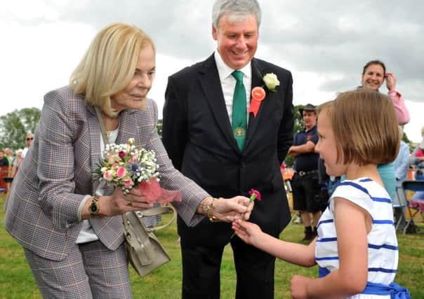 The Duchess of Kent hands a flower from her posy to Ebony Fairburn, aged four, who had presented the bouquet to the Duchess, as Chris Leckenby, joint president of the 150th Ryedale Show watches on.