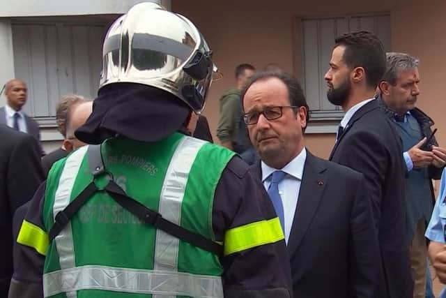 French President Francois Hollande speaks with emergency services personnel after arriving at the scene of the hostage situation in Normandy