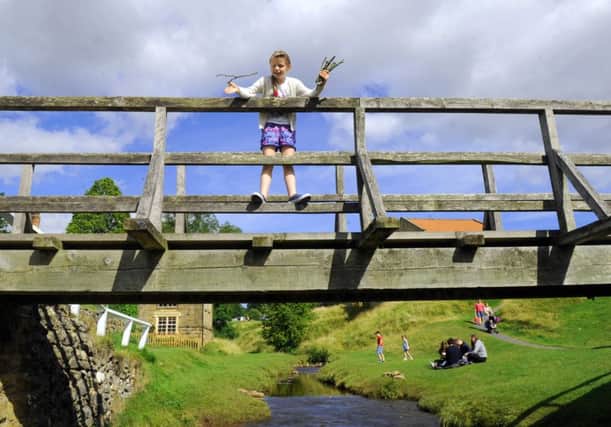 Kirsten Whatley-Bell,  from Doncaster playing pooh sticks on the bridge at Hutton le Hole  in North Yorkshire last year.