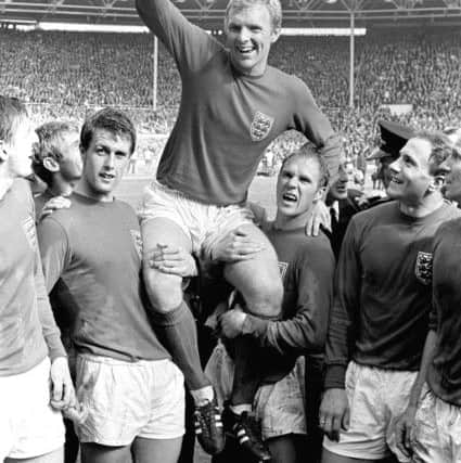 England's triumphant 1966 World Cup final captain Bobby Moore chaired by hat-trick hero Geoff Hurst (L) and Ray Wilson as he salutes the crowd with the Jules Rimet Trophy after the 4-2 victory against West Germany at Wembley.