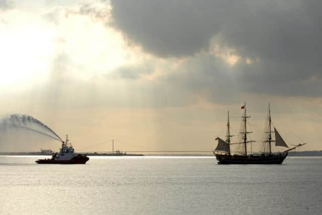 The replica HMS Bounty makes her way up the River Humber towards Albert dock, Hull last night accompanied by a water-spraying tug _ with the Humber Bridge in the background _ in preparation for this weekend's Maritime Festival. Picture: Terry Carrott
