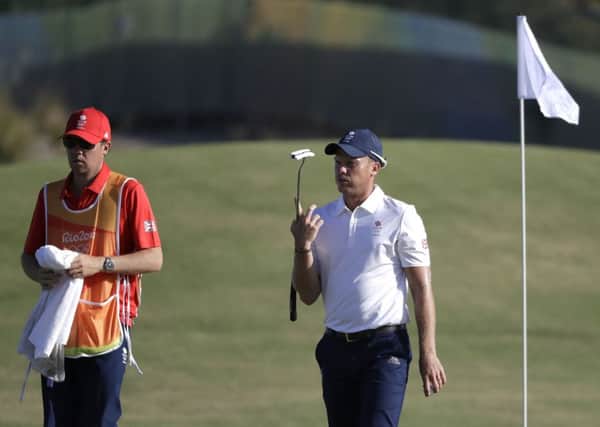 Danny Willett, of Great Britain, twirls his putter as he walks off the 16th hole with his caddie, Jonathan Smart, left.