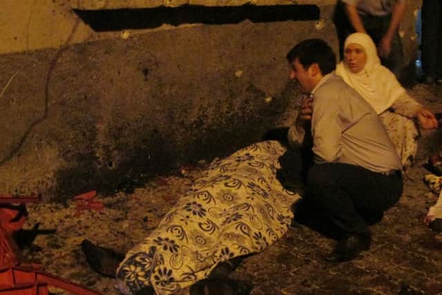 A man cries over a covered body after an explosion in Gaziantep, southeastern Turkey, late Saturday night.