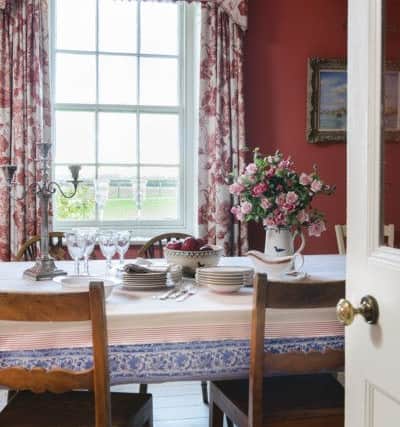 The dining table is an old kitchen table topped with wood and a pretty tablecloth made from fabric.