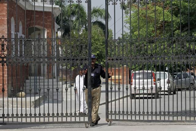 A Pakistani police officer closes the main gate of the district courts, where the proceeding in a British woman's murder case is being held, in Jhelum, eastern Pakistan