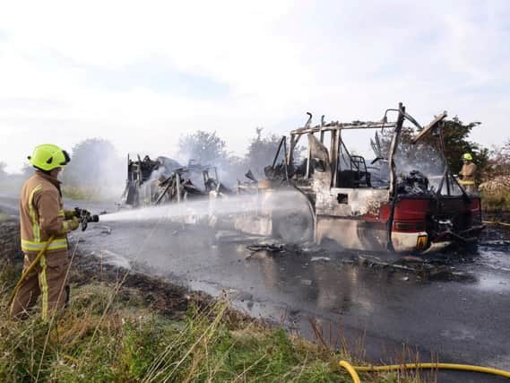 Firefighters attend to the remains of the school bus. Picture: Paul Atkinson/Ross Parry Agency