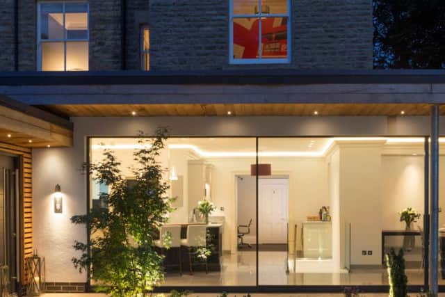 The rear, single storey extension clad in cedar, render with a wall of glass sliding doors.