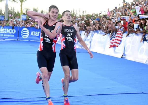 Britain's Alistair Brownlee, left, helps his brother Jonny to get to the finish line during the Triathlon World Series event in Cozumel, Mexico. (Delly Carr via AP)