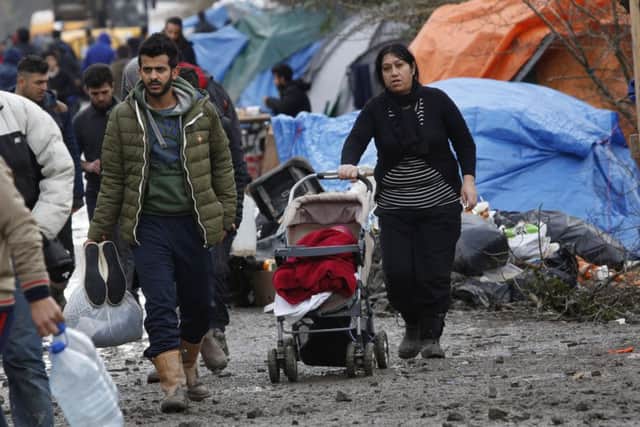 A migrant family walk in the mud in a makeshift camp where over 1,000 migrants mostly from Iraqi Kurdistan live in Grand-Synthe, near the northern town of Dunkerque, France. (AP Photo/Jerome Delay)