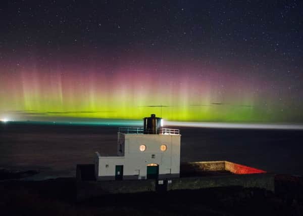The Northern Lights, or Aurora Borealis appear in the sky over Bamburgh lighthouse at stag Rock in Northumberland. PIC: PA