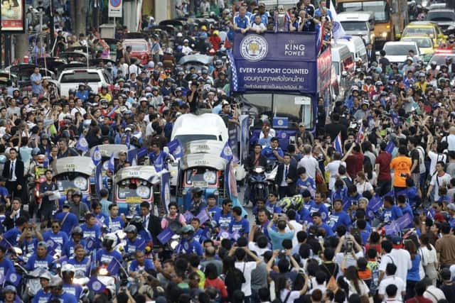 Crowds line the street to cheer on Leicester City players and staff celebrate with the trophy after winning the English Premier League during an open top bus parade through the central business district of Bangkok, Thailand, Thursday, May 19, 2016. The Leicester City team is on a two-day visit to Bangkok to celebrate their premiership win. (AP Photo/Mark Baker)
