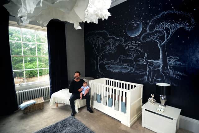 Nick with baby Rex Valentine in the nursery,  decorated with a mural
