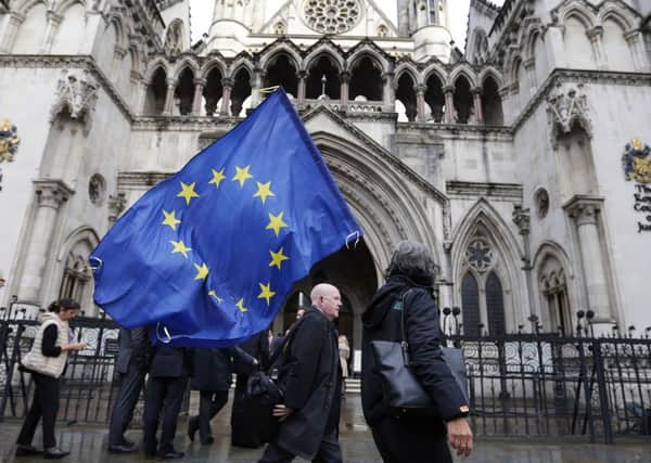 A Pro-EU membership supporter walks outside the High Court, where lawyers are battling over whether the government has the power to trigger Britain's exit from the European Union without approval from Parliament. (AP Photo/Frank Augstein)