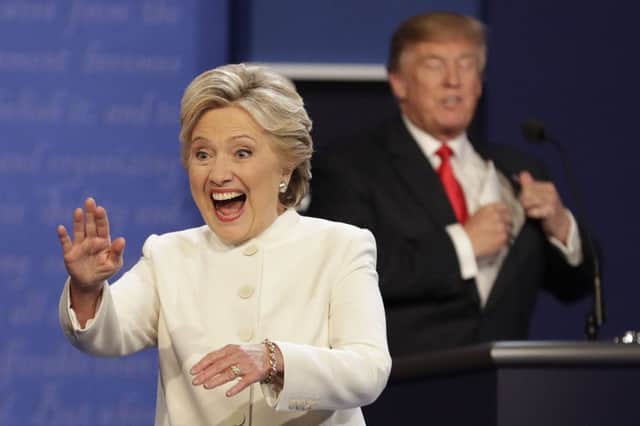 Hillary Clinton waves to the audience as Republican presidential nominee Donald Trump puts his notes away after the third presidential debate