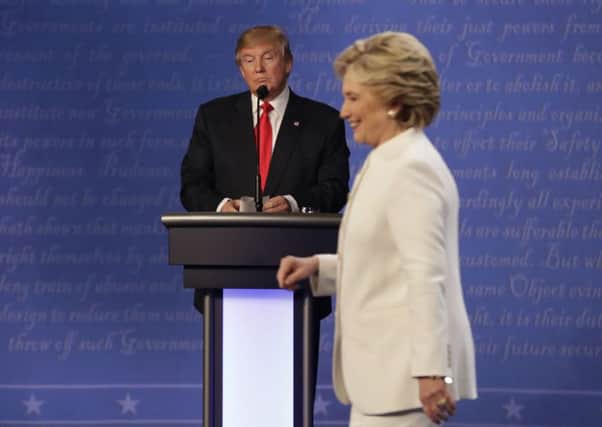 Republican presidential nominee Donald Trump waits behind his podium as Democratic presidential nominee Hillary Clinton makes her way off the stage following the third presidential debate at UNLV in Las Vegas.