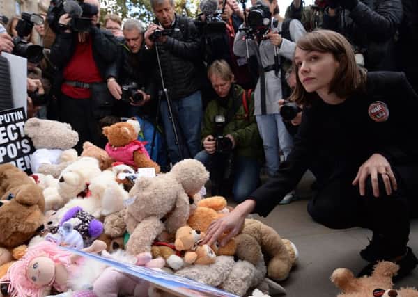 Actress Carey Mulligan leaves a teddy bear outside the gates of  Downing Street in central London during a protest to highlight the high numbers of children killed in bombings in Syria and to demand the Government intervene over Russian and Syrian bombing campaigns.