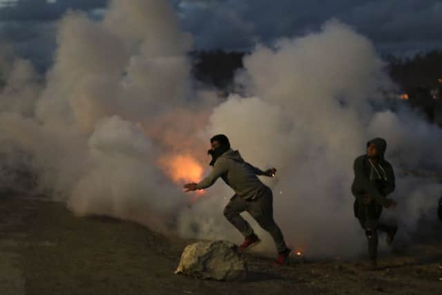 Demonstrators throw back tear gas canisters to French riot police officers during clashes in a makeshift migrant camp known as "the jungle" near Calais, northern France, on Saturday, Oct. 22, 2016. French authorities say the closure of the slum-like camp in Calais will start on Monday and will last approximatively a week in what they describe as a "humanitarian" operation.