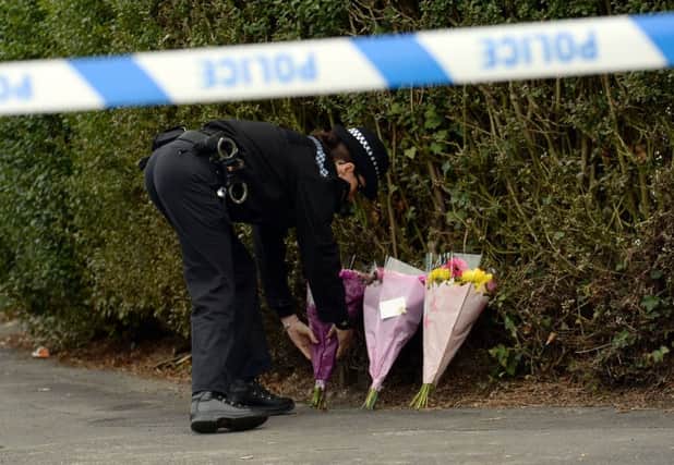 A police officer lays flowers at the scene at Byron Avenue in Campsall, South Yorkshire, where the body of a 13-year-old boy has been found following a fire in a shed.