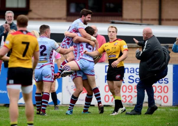 Rotherham Titan players Will Goodwin and Matt Walsh celebrate on top of team-mate Jake Henry after he scored a vital try.