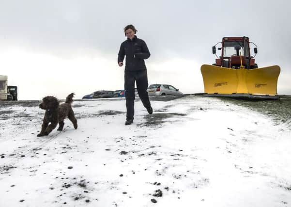 A woman walks her dog following a light dusting of snow at Tan Hill in North Yorkshire.