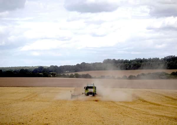 A combine harvester works in a field of barley.  Pic: Steve Parsons/PA Wire
