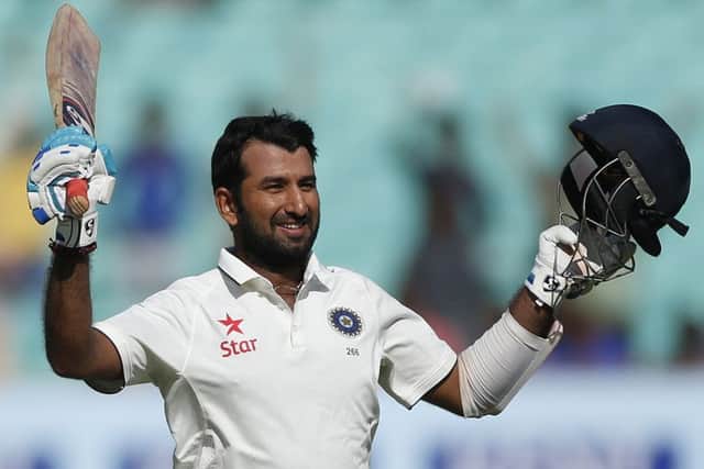 Indian batsman Cheteshwar Pujara raises his bat and helmet after scoring a century (AP Photo/Rafiq Maqbool)