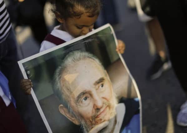 Maia Marti holds a poster of Fidel Castro  as she waits in line to pay her final respects to the late Fidel Castro at Revolution Plaza, in Havana.