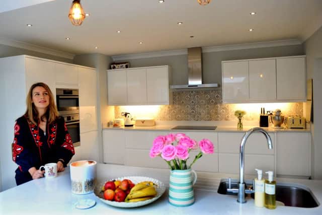 Nicola in the kitchen area of her open plan living space. The units are livened up with decorative tiles.