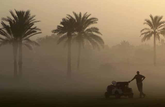 An official looks through the early morning fog at the Dubai Ladies Masters golf tournament