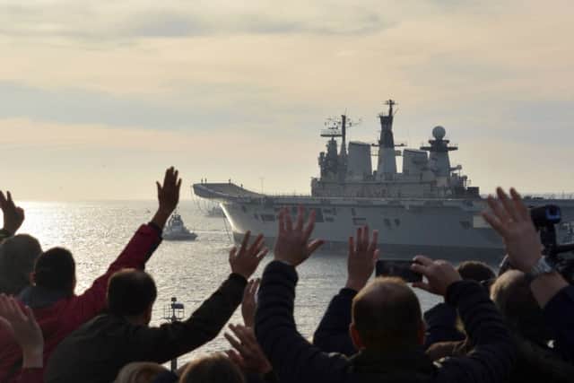 People wave as the Royal Navy's former aircraft carrier HMS Illustrious is towed out of Portsmouth Harbour heading for a Turkish scrapyard.