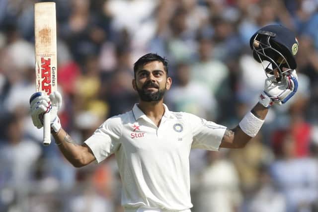 Indian cricket captain Virat Kohli raises his bat and helmet after scoring double century on the fourth day of the fourth cricket test match between India and England in Mumbai. (AP Photo/Rafiq Maqbool)
