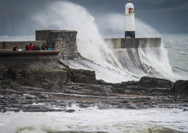 People watch waves crash over the harbour wall at Porthcawl, South Wales.
