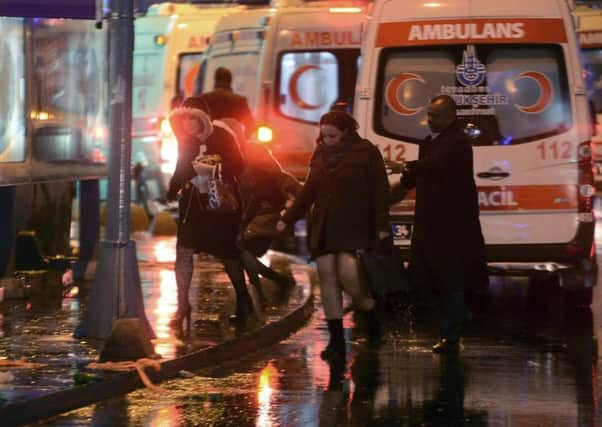 People leave as medics and security officials work at the scene after an attack at a popular nightclub in the Turkish city of Istanbul