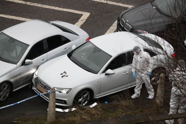 Police forensics officers examine a silver Audi with bullet holes in its windscreen at the scene near junction J24 of the M62 in Huddersfield where a man died in a police shooting during a "pre-planned" operation