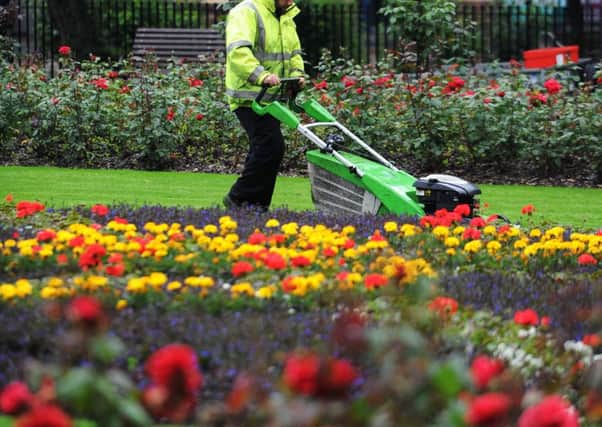 A workman cutting the grass in a Leeds park.