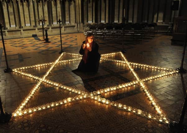 Vicky Harrison (from York Minster) lights a candle in the Chapter House of York Minster within the candles depicting the Star of David to mark Holocaust Memorial Day.