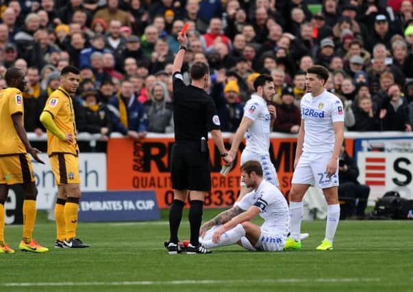 Leeds United captain Liam Copper, sat on ground, is shown a red card in the defeat at Sutton United (Picture: Jonathan Gawthorpe).