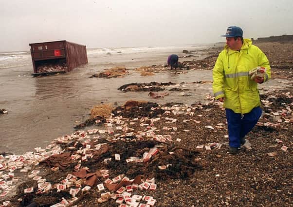 A customs officer keeps an eye as cigarettes are washed up from the beached container at Fraisthorpe nudist beach, near Bridlington. Picture: Terry Carrott