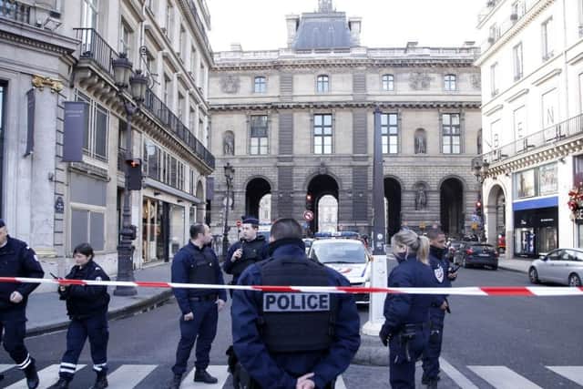 Police officers cordon off the area next to the Louvre museum in Paris