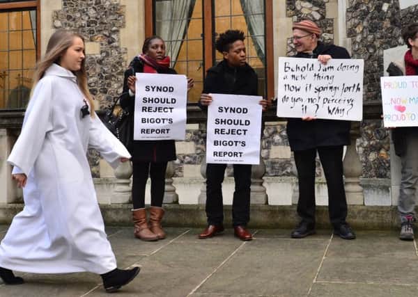 A delegate walks past activists from the Lesbian and Gay Christian Movement outside the General Synod at Church House in London, where a Church of England report on same sex marriage was discussed.