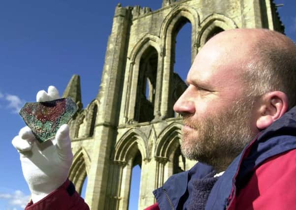 Bob Smith, Collections Photographer for English Heritage, looks at the 13th century stained glass which shows a red cockerel. The glass was found during excavations at Rievaulx Abbey near Helmsley in North Yorkshire and is thought to have come from one of the abbey's east end windows, pictured.   oct 7 2003