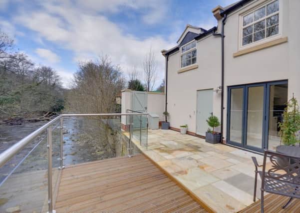 The cottage transformed with an extension and a cantilevered balcony over the river.